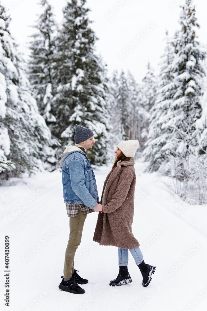 Man and woman looking at each other in winter forest.