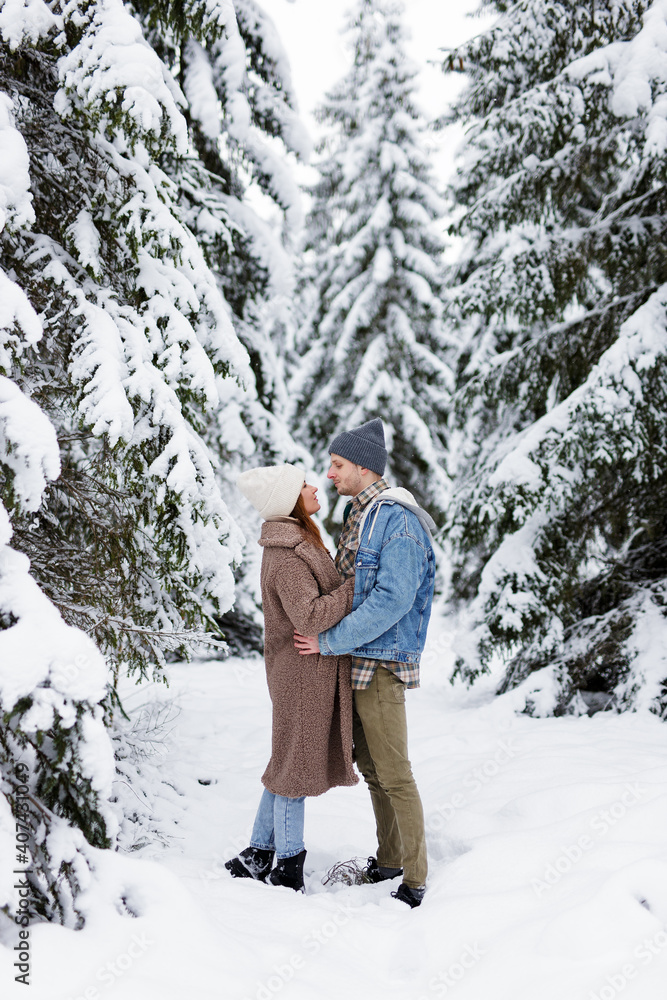couple looking at each other and embracing in winter forest