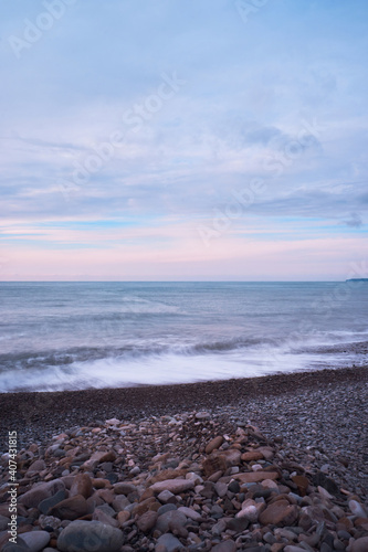 Beautiful sea landscape. Blue pink purple sunset sky over sea coast with pebble beach.