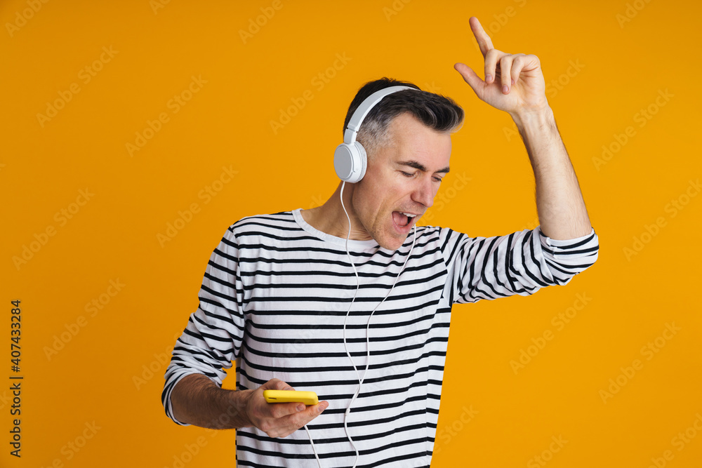 Joyful man in headphones dancing and using mobile phone Joyful man in headphones dancing and using mobile phone