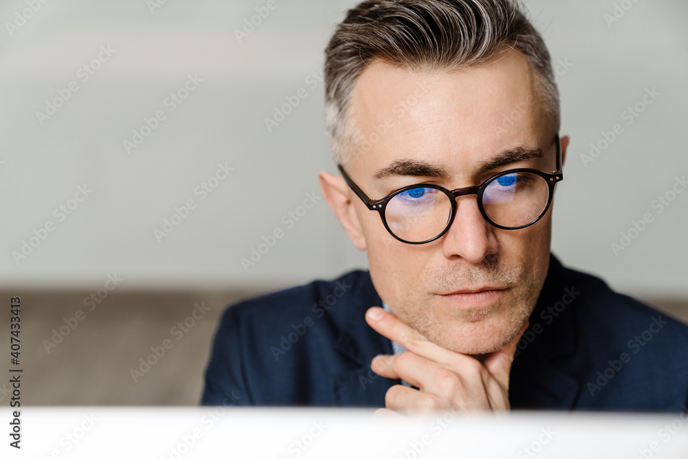 Concentrated grey man in eyeglasses working with computer at office Concentrated grey man in eyeglasses working with computer at office