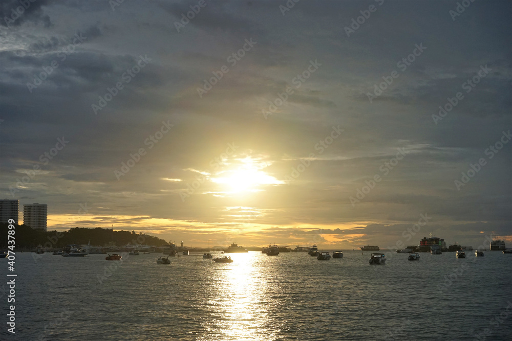 Tropical beach at dusk with many boats on the sea in Pattaya, Thailand