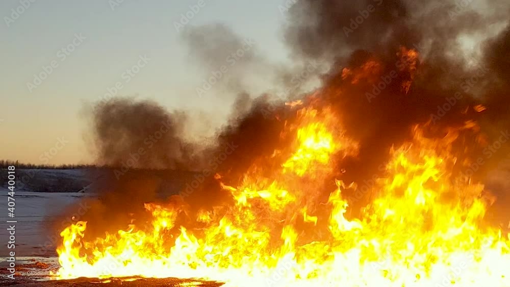 Close up of huge raging flames burning and creating thick black billowing clouds of dark smoke. Close up of huge raging flames burning and creating thick black billowing clouds of dark smoke.