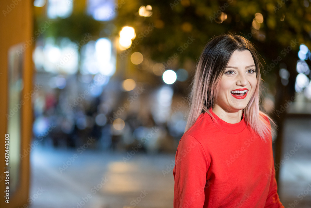 Bella ragazza bionda con maglione rosso sorride divertita in contesto urbano