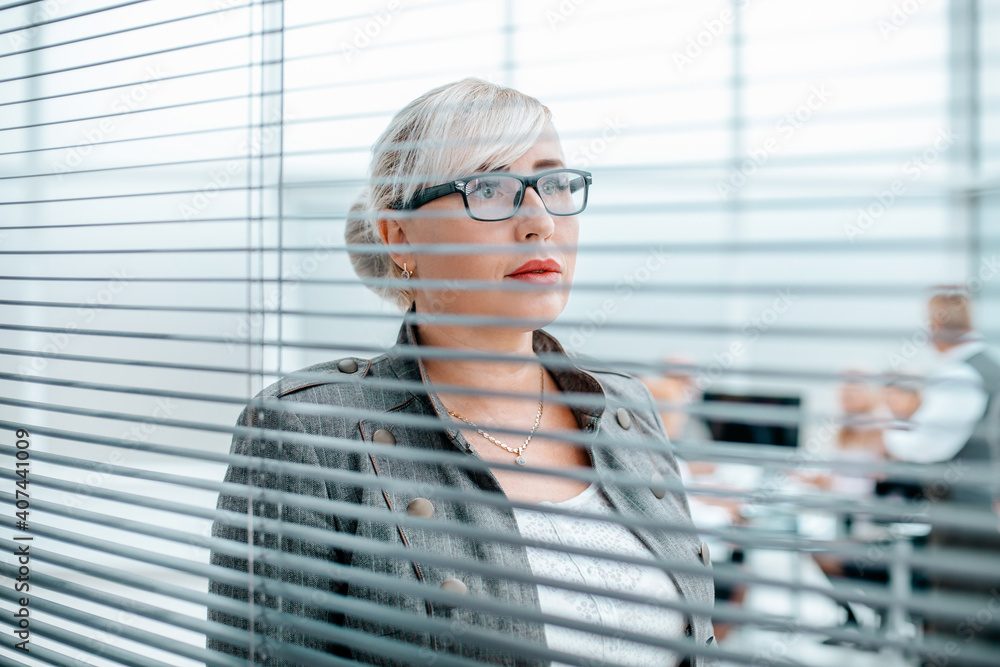 close up. serious business woman looking through office window