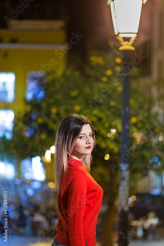 Bella Modella bionda con maglione rosso guarda sensuale, in contesto urbano notturno
