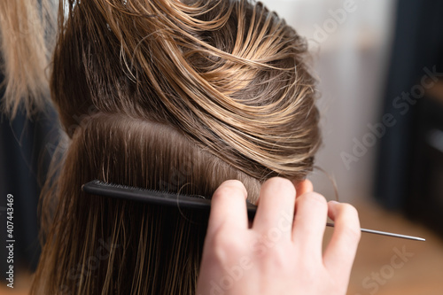 Hairdresser checking blonde womens regrown roots. Preparing for hair coloring and hair cutting at home or at salon.