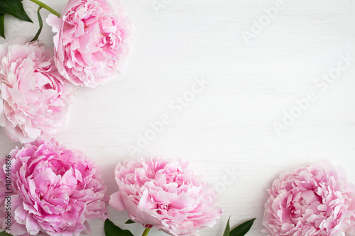 White wooden background with pink peonies with space for text.