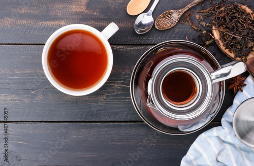 Top view of hot tea in a jug and in a teacup placed on a vintage wood floor.