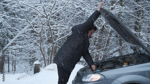 Woman opening bonnet of broke down car to check engine