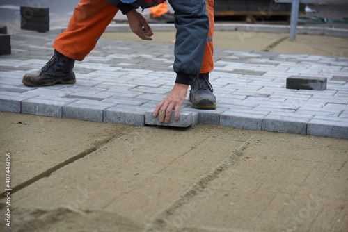 Laying cement paving stones, a worker builds a new road for pedestrians.