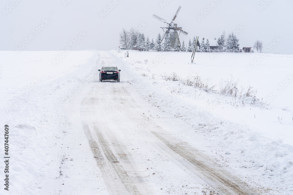 The car is going to the windmill in snowy day