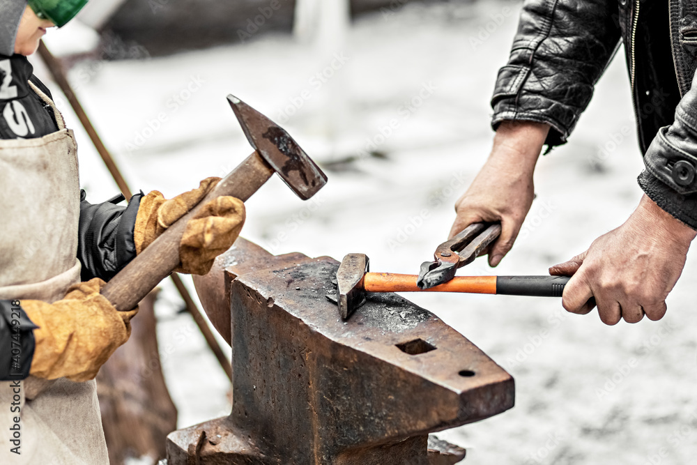 A blacksmith man and his son forge a horseshoe on an anvil. A blacksmith man and his son forge a horseshoe on an anvil.