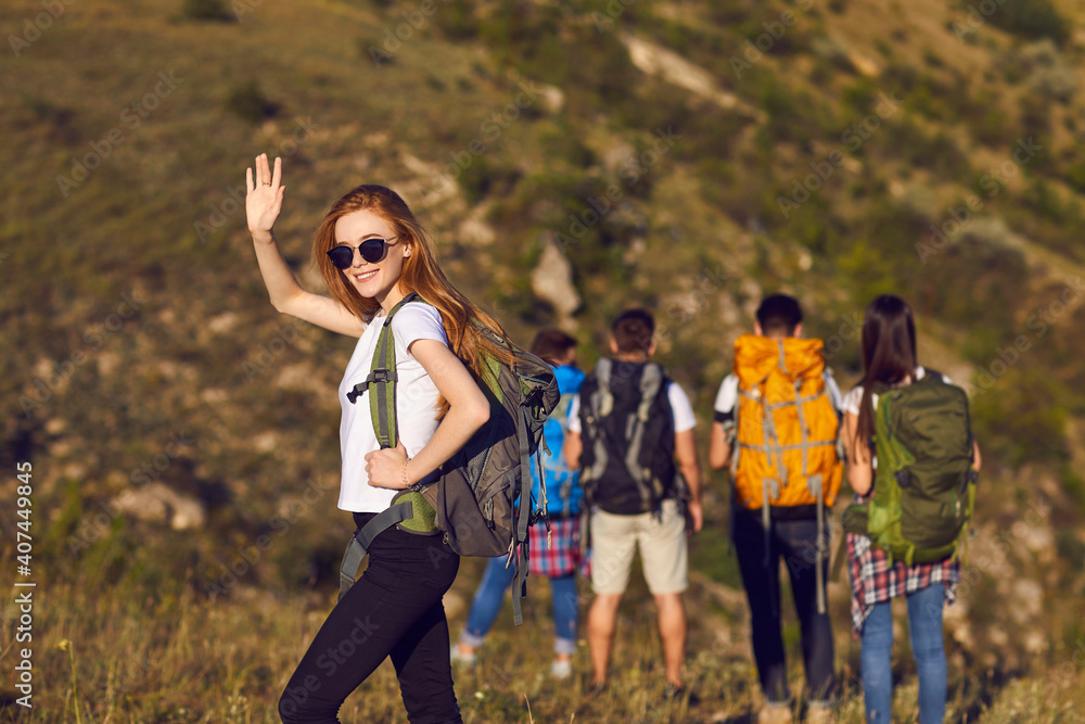 Smiling girl tourist hiker with backpack standing and waving with hand during hiking Smiling girl tourist hiker with backpack standing and waving with hand during hiking