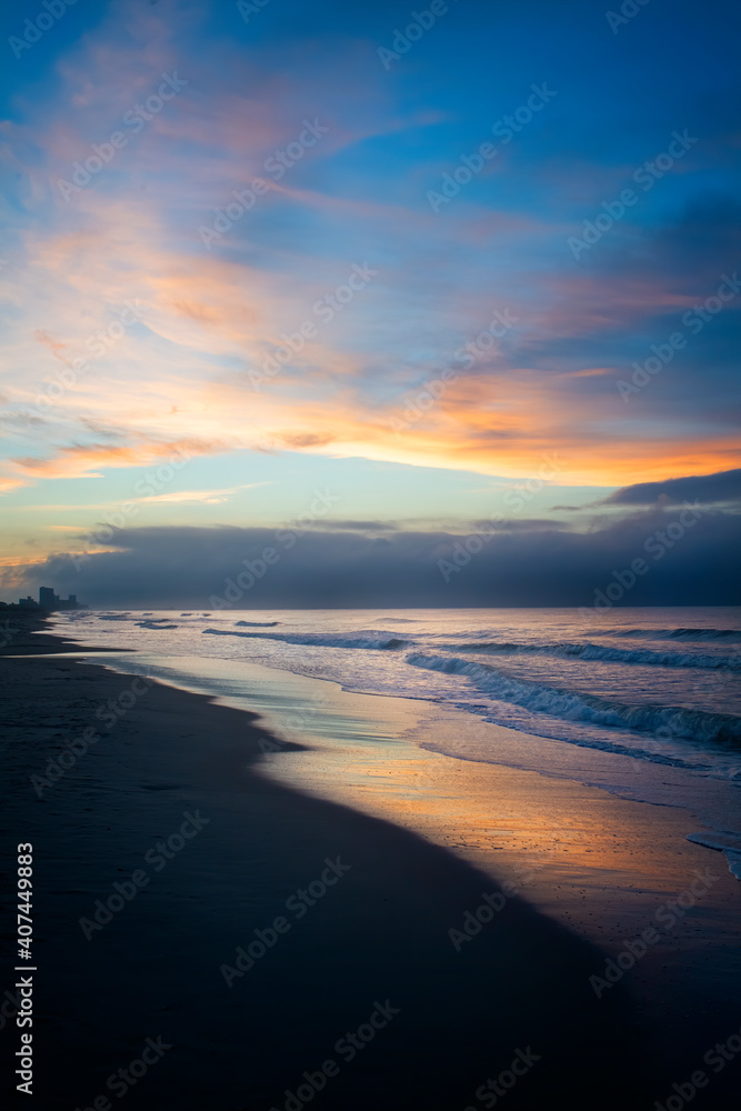 reflection of the clouds and sky on the wet beach at sunrise