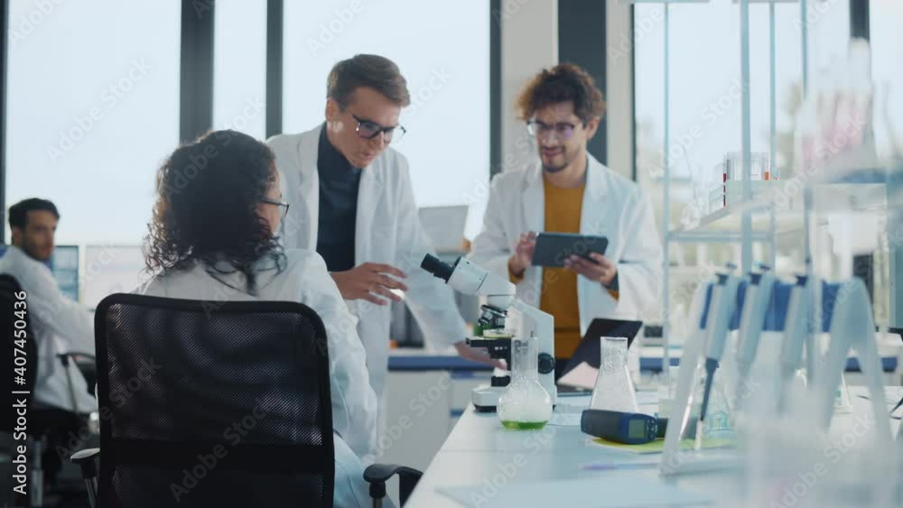 Medical Science Laboratory: Black Scientist Looking Under Microscope, Discovers New Medicine, Does High Five, Celebrates with Colleagues. Brilliant Young Specialists, Doing Innovative Research Medical Science Laboratory: Black Scientist Looking Under Microscope, Discovers New Medicine, Does High Five, Celebrates with Colleagues. Brilliant Young Specialists, Doing Innovative Research