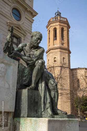 Joan Sallares and Pla monument (1917) by sculptor Josep Clara at Placa del Doctor Robert in Sabadell, Catalonia, Spain. Tower of the Church of Sant Felix on the background