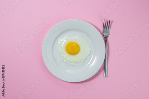 Scrambled eggs on a pink background. Fried eggs on a white plate. Tasty breakfast.