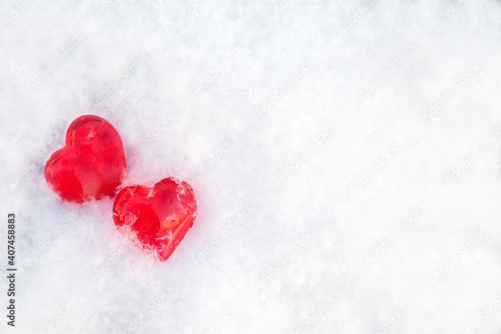 two red hearts lie on the white snow. valentines day holiday concept