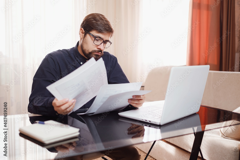 Entrepreneur works with a laptop and keeps a document in a home office Entrepreneur works with a laptop and keeps a document in a home office