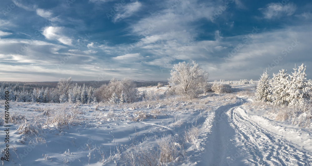 Snowy road at winter Stone Hill park in frosty sunny evening. Winter country road with fir forest in the rays of cold winter Sun. Snowy road at winter Stone Hill park in frosty sunny evening. Winter country road with fir forest in the rays of cold winter Sun.