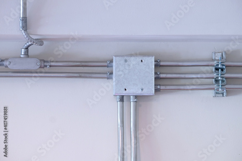 Steel conduit box and pipes installed on white wall