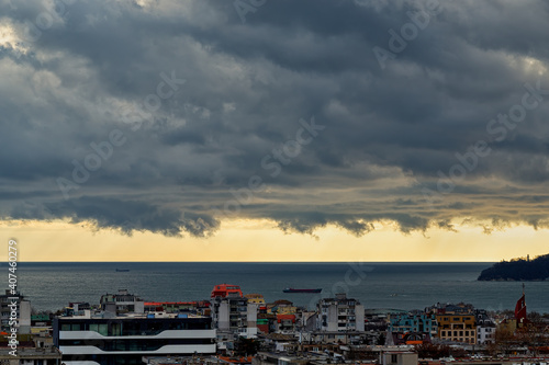 Dramatic landscape of stormy sky over small seaside city. The sky turned yellow before the storm. Dark nimbostratus clouds hang over town and sea. Weather forecast and meteorology.
