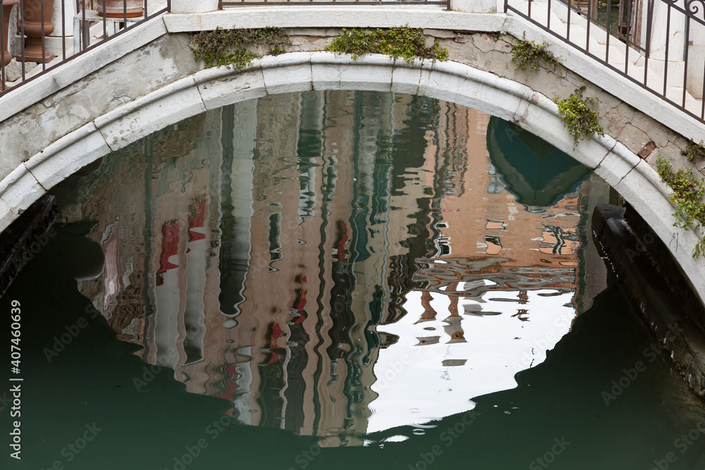 Reflections of Venitian houses under a typical pedestrian bridge, Venice, Italy