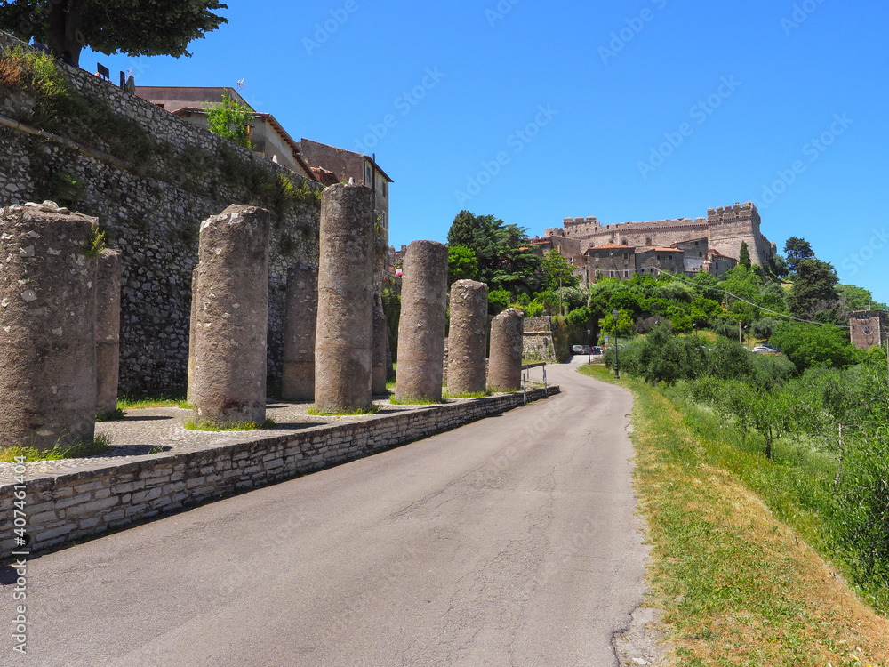 Beautiful Italian landscape. Famous castle of Caetani family on mountain top and old medieval houses. Remains of ruined columns and large defensive wall surrounding small, ancient town Sermoneta.