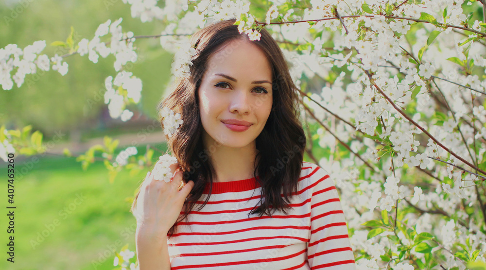Portrait close up of beautiful young woman in a spring blooming garden on a white flowers background Portrait close up of beautiful young woman in a spring blooming garden on a white flowers background