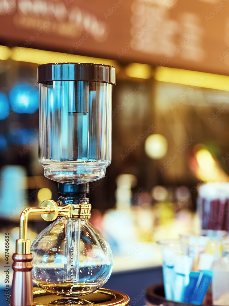 Close up to barista make coffee with Vacuum Pot Syphon Brewer.  Syphon (Siphon) coffee maker brews drink using two chambers where vapor pressure and vacuum produce coffee in cafe. Selective focus.