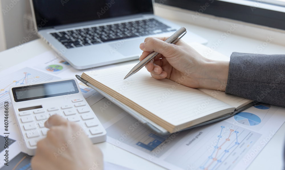 Head of accounting is recording the company's financial growth statistics using graphs as a reference for reviewing and analyzing the results, Taking notes and analyzing data graphs in office. Head of accounting is recording the company's financial growth statistics using graphs as a reference for reviewing and analyzing the results, Taking notes and analyzing data graphs in office.