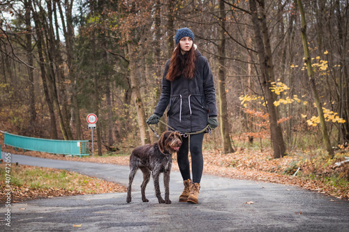 bond between the lady and her dog. Candid portrait of a young brunette and her Bohemian Wire-haired Pointing Griffon dog in the wild. Walk on the road. The intimate bond between animal and human © Fauren