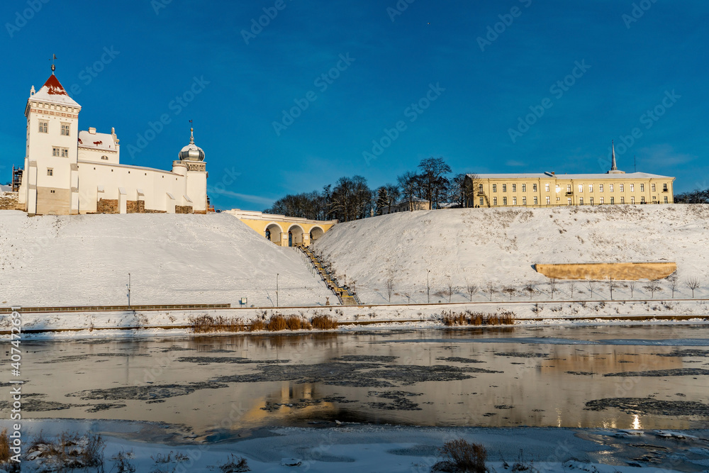 An old building in the city on a hill on the riverbank in winter. Restoration of the old castle. Monument of architecture and historical heritage.