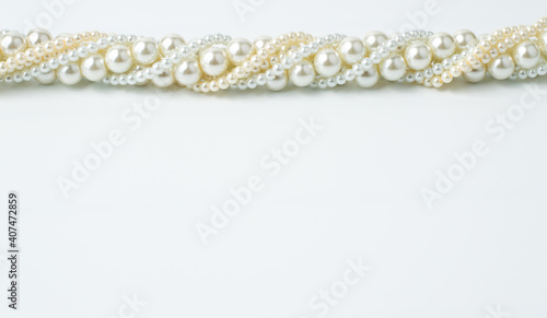 A necklace of beads of different sizes, white beige on a white background with a place to write the text.