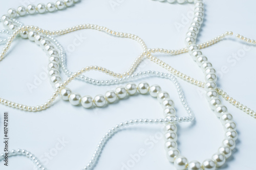 Blurred image of white beige necklaces with beads on a white background.