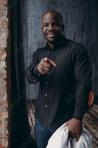 African american man showing finger to camera and holding white jacket while standing in apartment © DmitryStock
