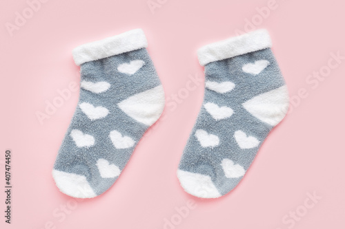 Pair of warm winter womens socks with print in the shape of hearts isolated over pink background. Valentine's day gift