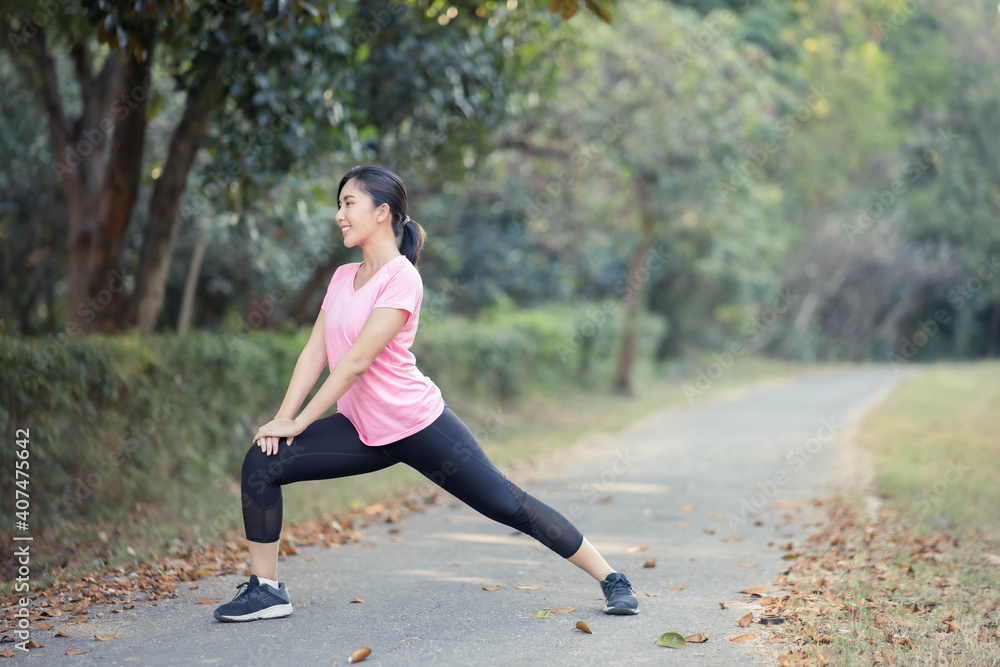 Asian girl is stretching her body warm muscles before going out for a run at the park Asian girl is stretching her body warm muscles before going out for a run at the park