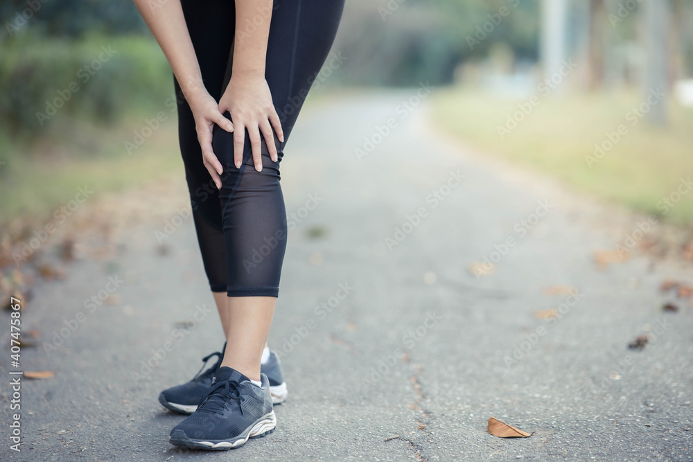 A young Asian woman sore knees after running. A young Asian woman sore knees after running.