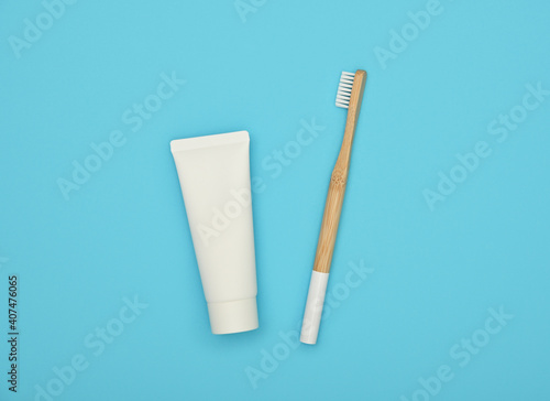 White toothpaste and bamboo toothbrush on blue