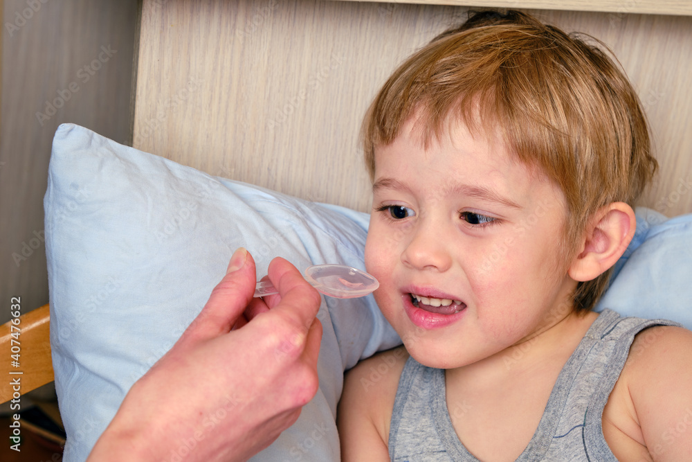 Sick child, toddler boy lying in bed with a fever, resting at home. Illness child. Doctor is using medicine Sick child, toddler boy lying in bed with a fever, resting at home. Illness child. Doctor is using medicine