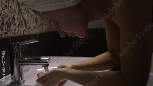 beautiful caucasian woman picks up water in her hands and washes her face