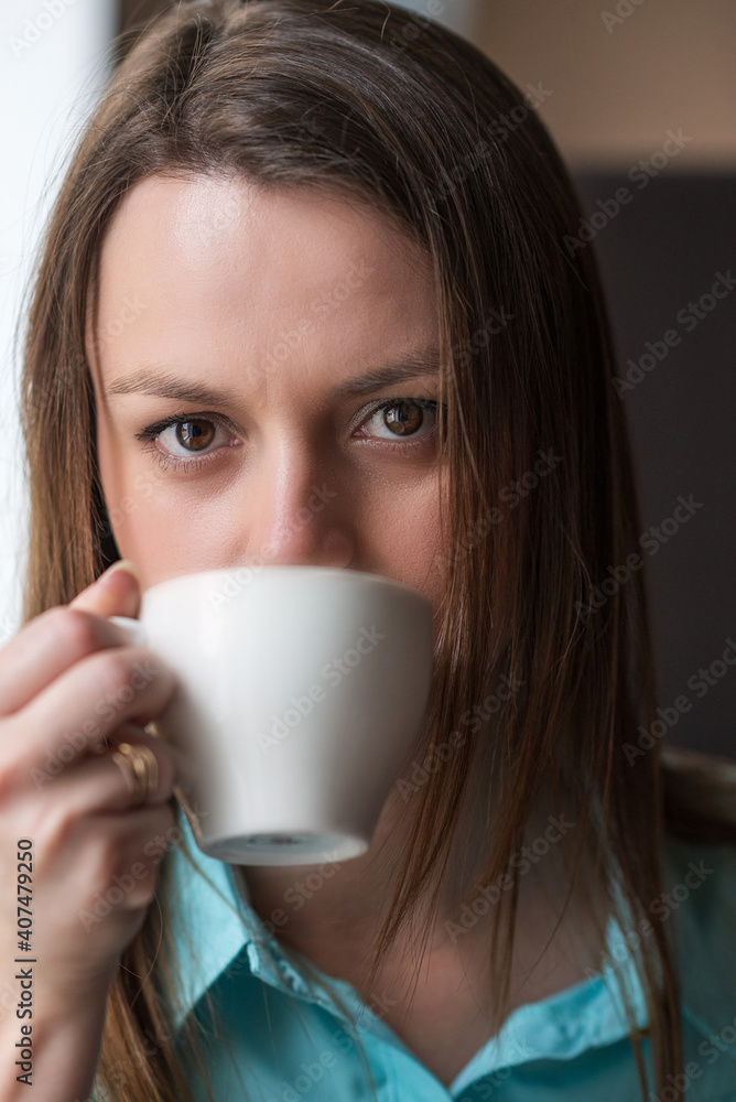 Young beautiful girl with brown hair drinks coffee in a cafe. Young beautiful girl with brown hair drinks coffee in a cafe.