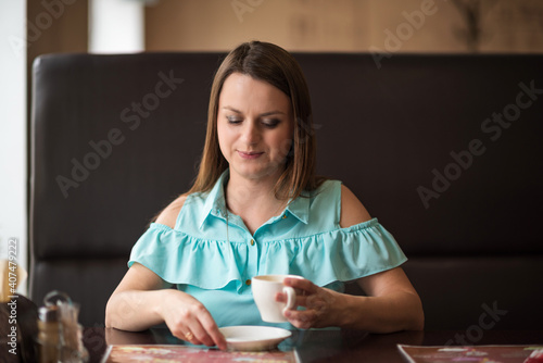 Young beautiful girl with brown hair drinks coffee in a cafe.