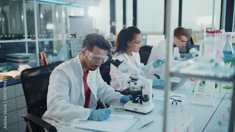 Modern Medical Research Laboratory: Portrait of Latin and Black Young Scientists Using Microscope, Digital Tablet, Doing Sample Analysis, Talking. Diverse Team of Specialists work in Advanced Lab Modern Medical Research Laboratory: Portrait of Latin and Black Young Scientists Using Microscope, Digital Tablet, Doing Sample Analysis, Talking. Diverse Team of Specialists work in Advanced Lab