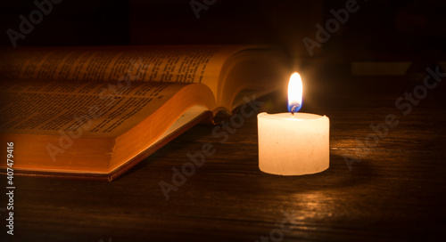 open bible in candle light. Bible and candle on the table.