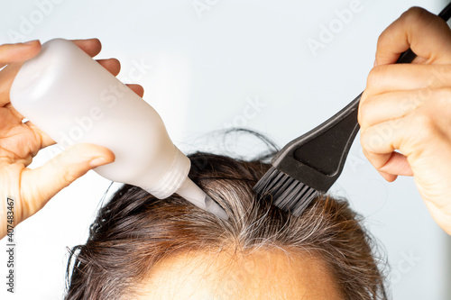 Photography Closeup woman hands dyeing hair using black brush