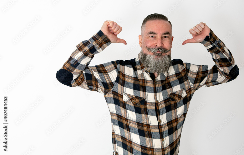 Naklejka premium Man with big beard and mustache, plaid shirt raising arms and pointing to himself with funny face and direct gaze