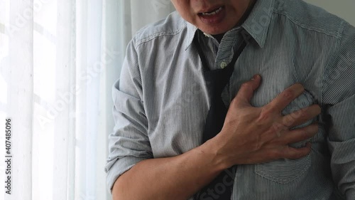 Asian business man with symptoms of heart disease. Chest pain on the left